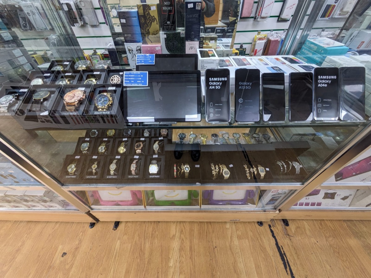 Glass counter at Sid Mobiles displaying new Samsung Galaxy phones, watches and fragrances.