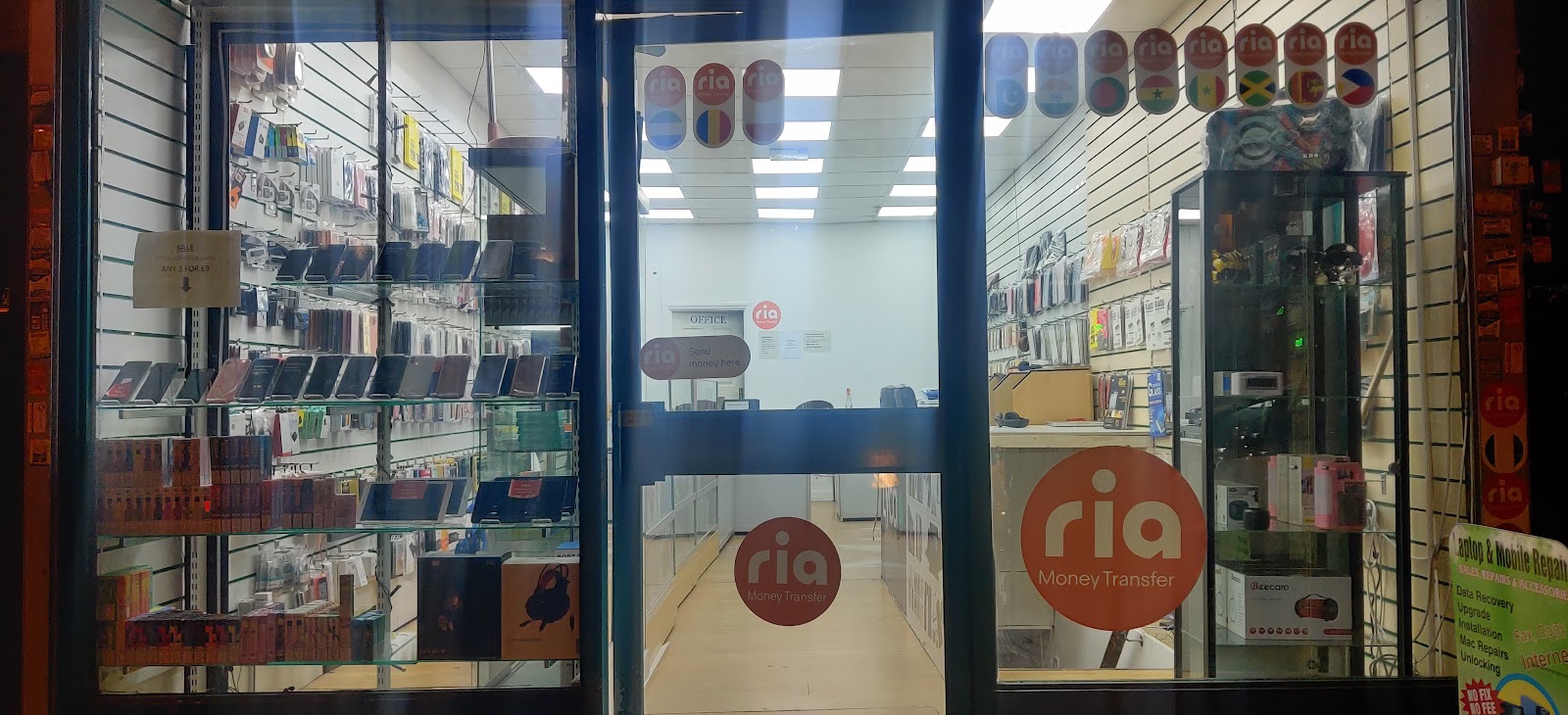 Inside Sid Mobiles, shelves of phone cases and accessories with a laptop and mobile repair sign listing sales, repairs, data recovery and unlocking.